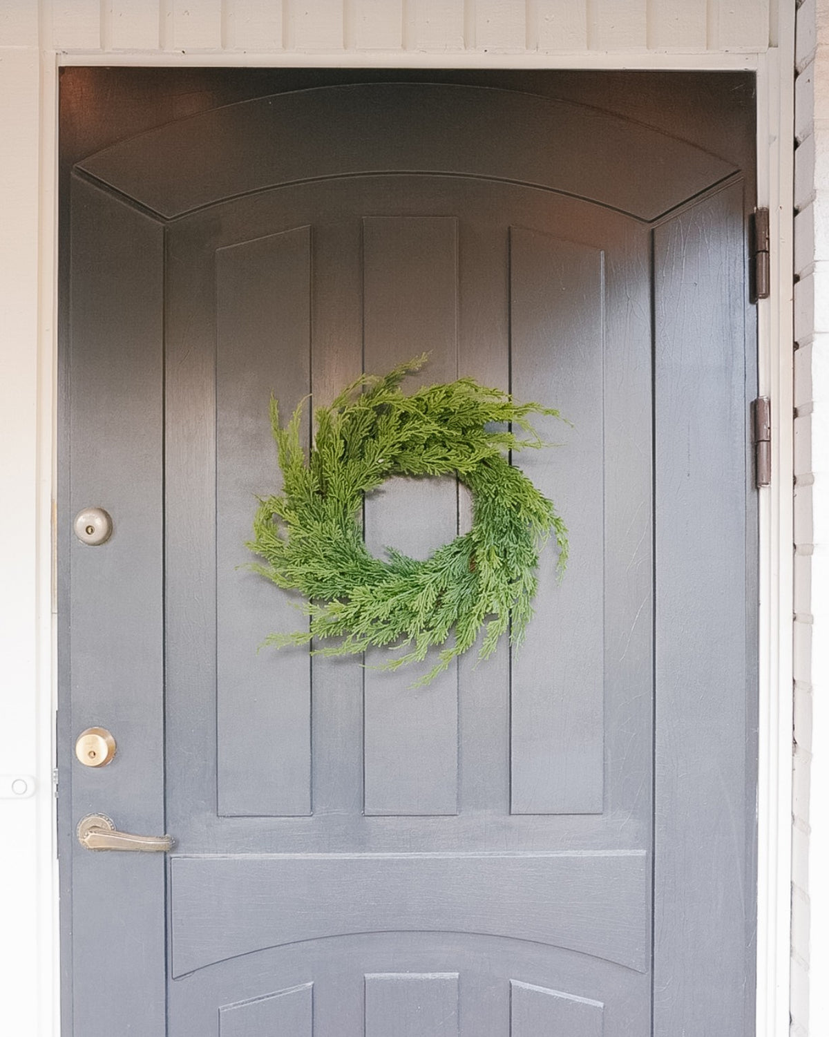 Small 40 cm silk evergreen wreath on a grey front door, front view