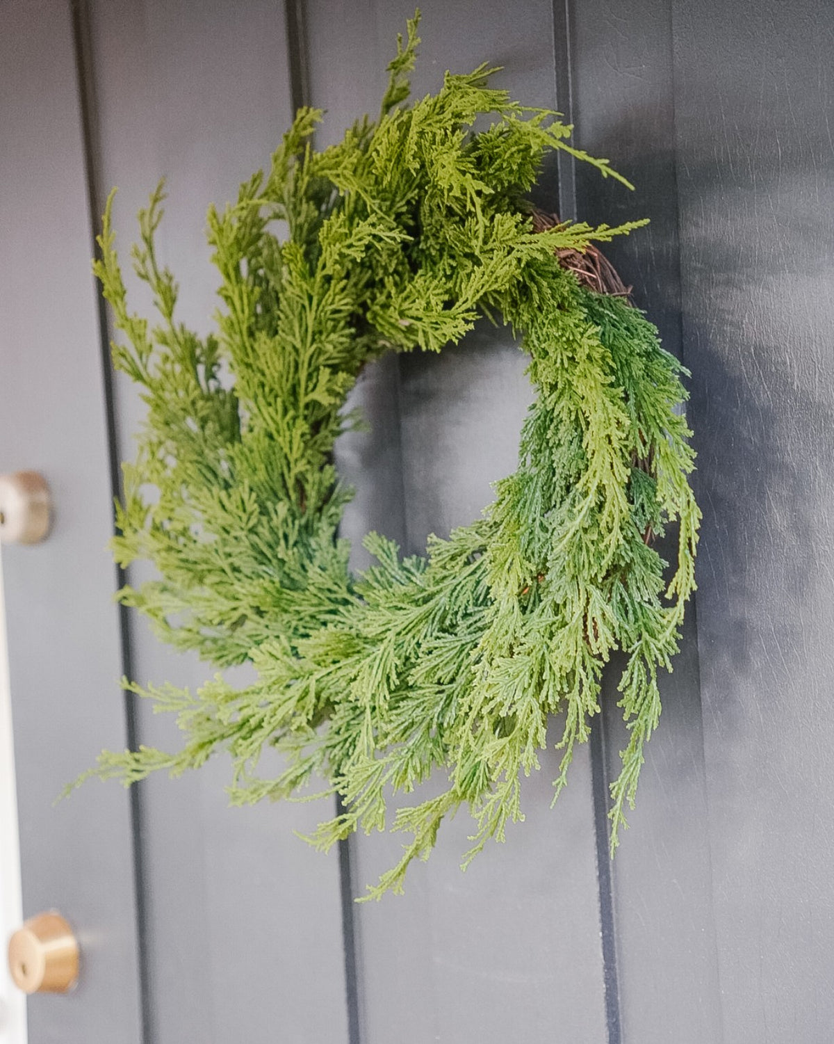 Close-up of a small 40 cm silk evergreen wreath on a grey door