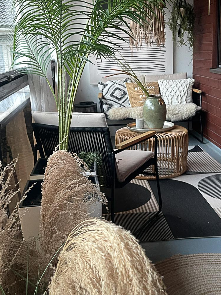 Glazed balcony styled with tall silk palms, ornamental grasses and natural materials. Lifelike everlasting plants bring greenery to a welcoming seating area