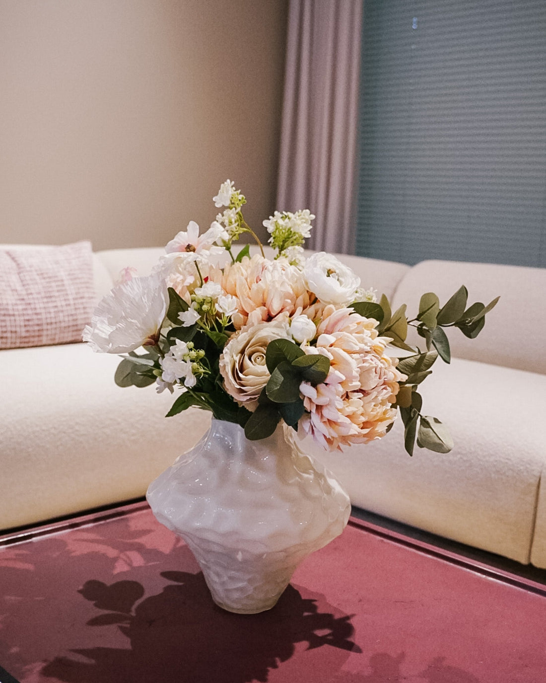 Pale, natural-looking silk flower bouquet on a living room table