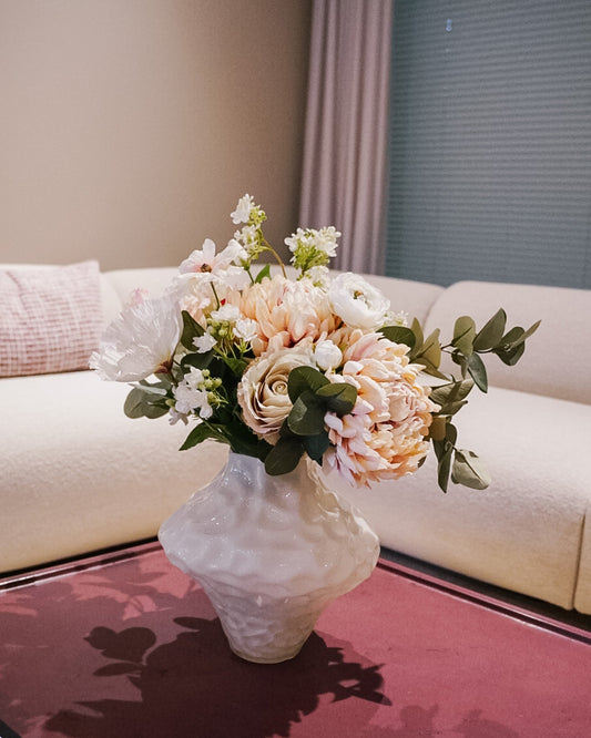 Pale, natural-looking silk flower bouquet on a living room table