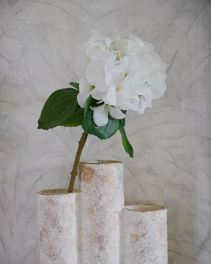 Valkoinen hortensia-silkkikukka vihreine lehtineen