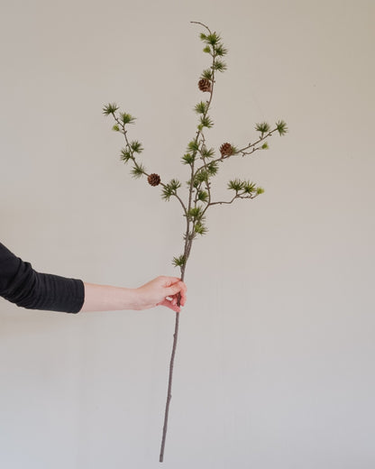 93 cm pitkä keinotekoinen lehtikuusenoksa kädessä