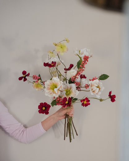 Saga silk flower bouquet held in hand, with white and burgundy flowers