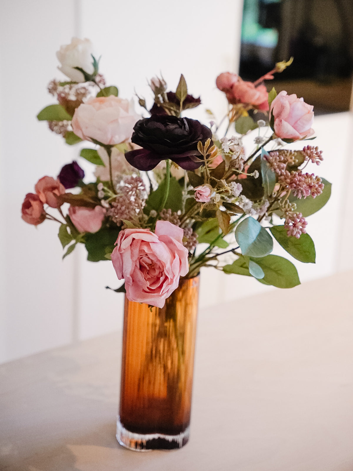 Violetta silk flower bouquet in an amber vase, with rose, burgundy and pale blooms